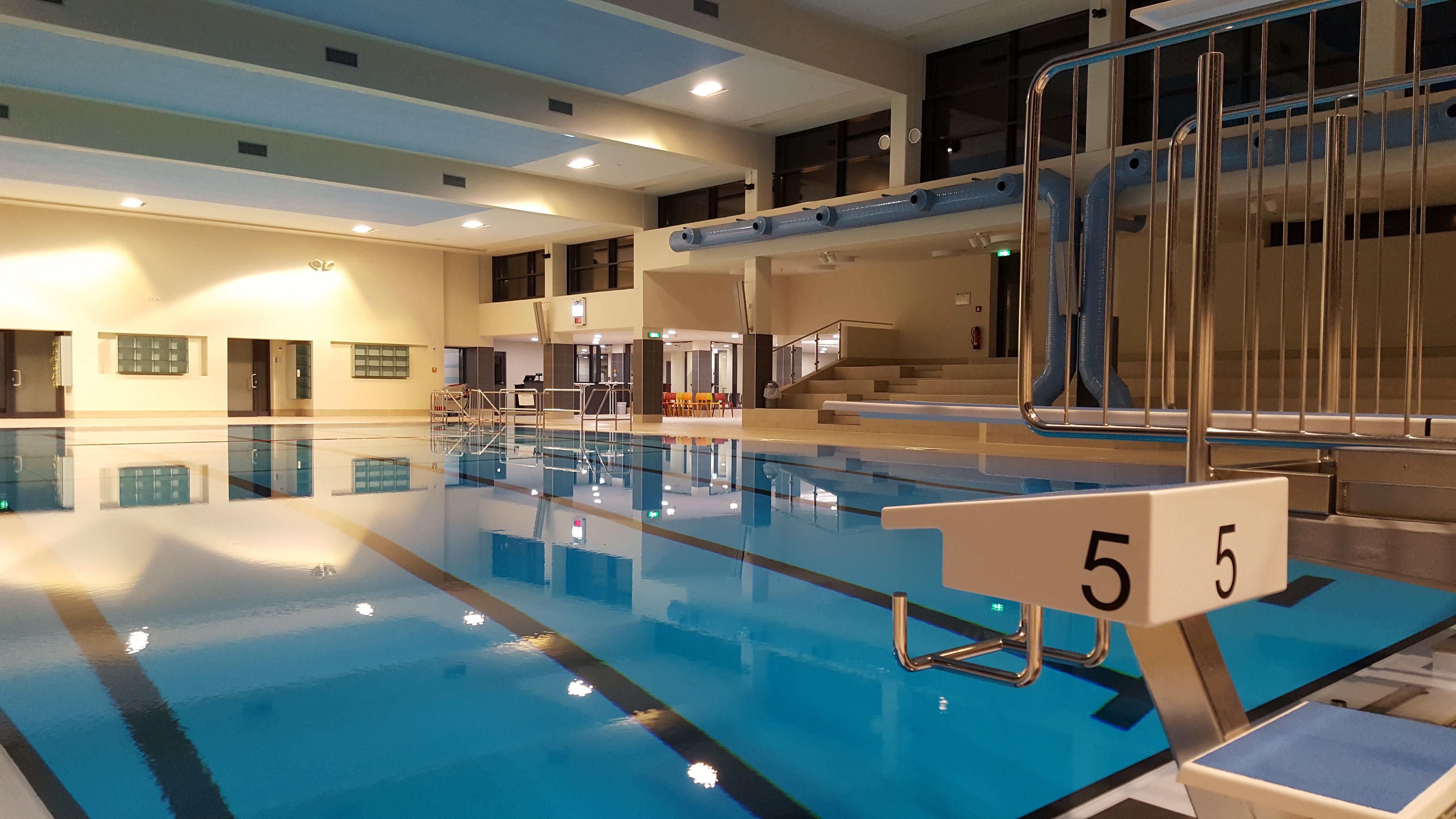 Blick vom Beckenrand auf das große Schwimmerbecken des Hallenbades.